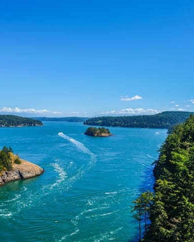 Turquoise lake surrounded by forested rocky shores and small islands under clear blue sky