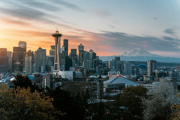 Seattle skyline at sunset with Space Needle, downtown skyscrapers, and snow-capped Mount Rainier in the distance